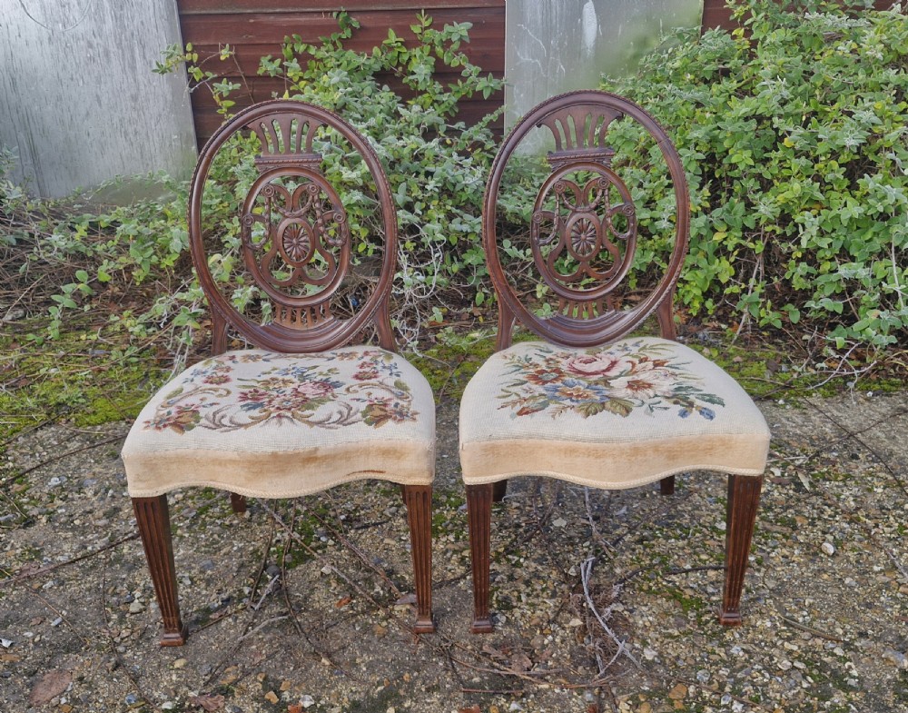 A pair of early 19th-century mahogany side chairs featuring carved oval backs, fluted legs, and floral needlepoint woolwork seats. View II