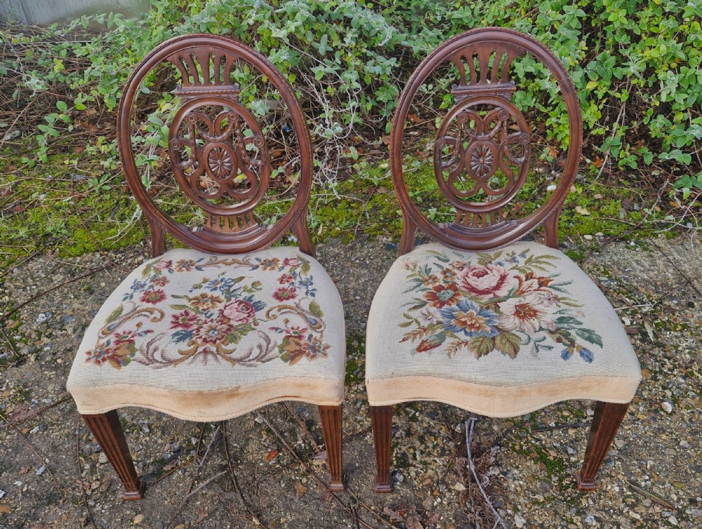 A pair of early 19th-century mahogany side chairs featuring carved oval backs, fluted legs, and floral needlepoint woolwork seats. View III