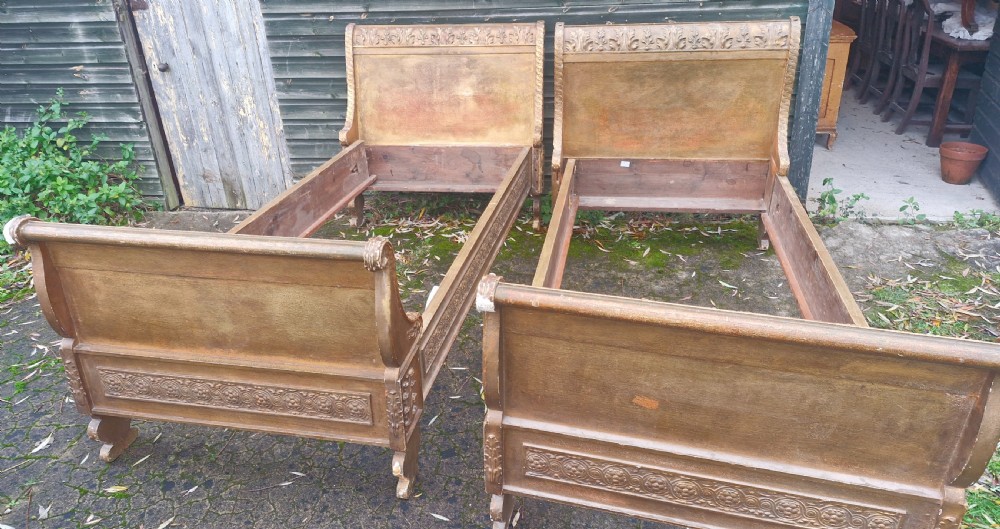 A pair of carved giltwood single sleigh beds featuring scrolled headboards, low scrolled footboards, and carved decorative friezes. View VI