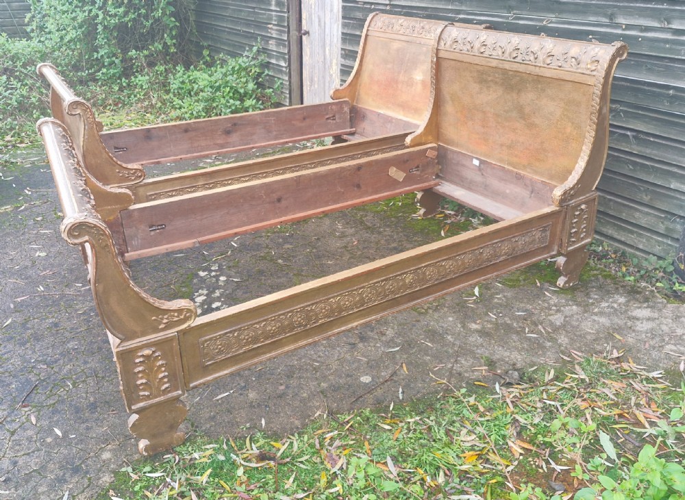 A pair of carved giltwood single sleigh beds featuring scrolled headboards, low scrolled footboards, and carved decorative friezes. View XIX
