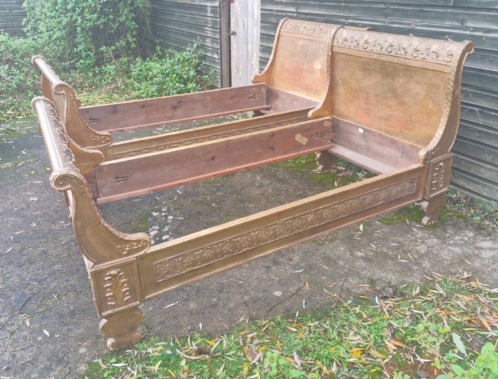 A pair of carved giltwood single sleigh beds featuring scrolled headboards, low scrolled footboards, and carved decorative friezes. View XXII