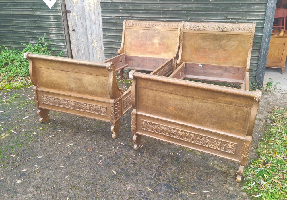 A pair of carved giltwood single sleigh beds featuring scrolled headboards, low scrolled footboards, and carved decorative friezes. View XXV
