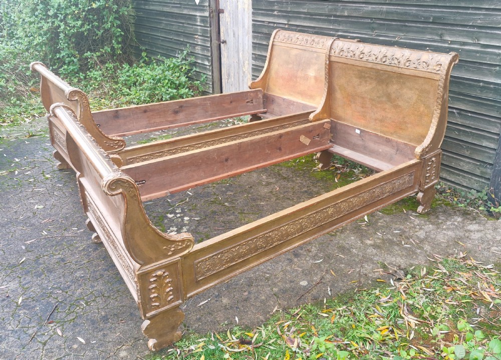 A pair of carved giltwood single sleigh beds featuring scrolled headboards, low scrolled footboards, and carved decorative friezes. View XXVII