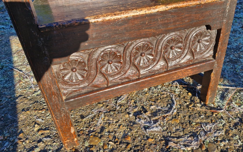 A dark carved oak childs wainscot armchair featuring a carved floral back panel, shaped armrests, and decorative carved seat rail. View III