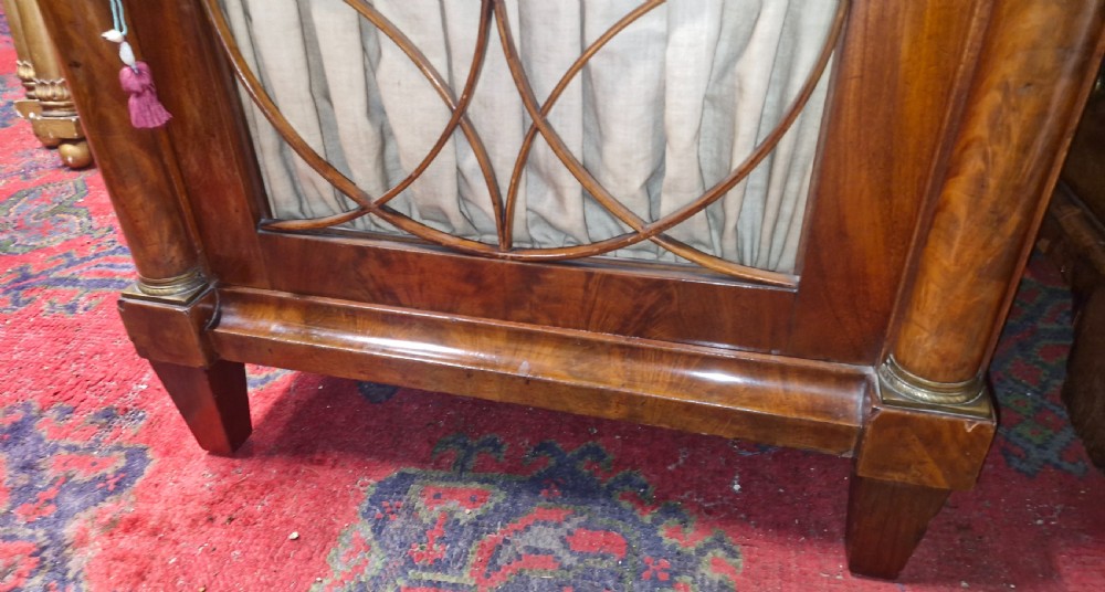 An Early Victorian mahogany single door side cabinet featuring a flame mahogany top and a decorative geometric fretwork door panel backed with fabric. View XV