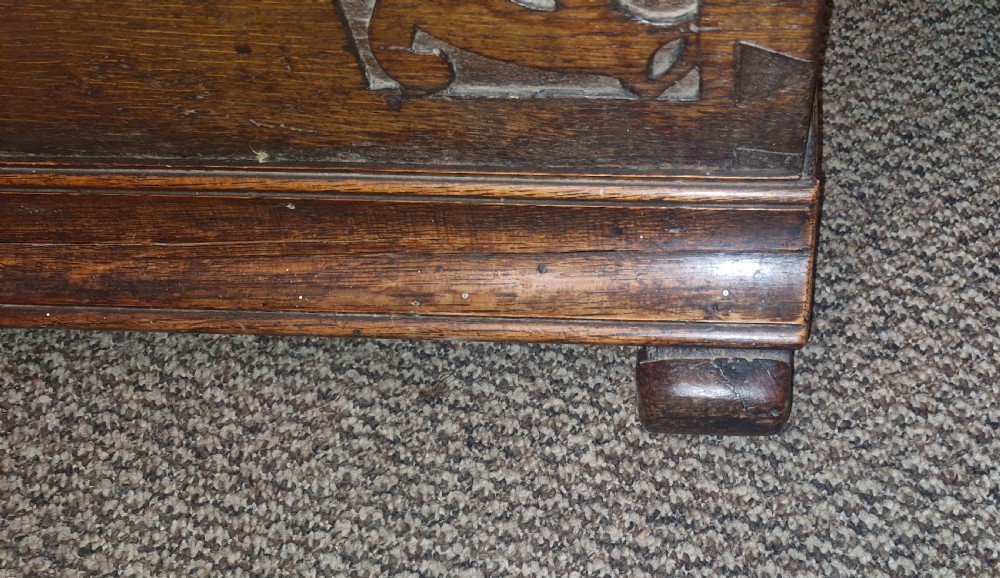A dark brown 18th-century carved oak blanket chest featuring rosette relief carvings, a carved top frieze, and a central iron escutcheon. View VII