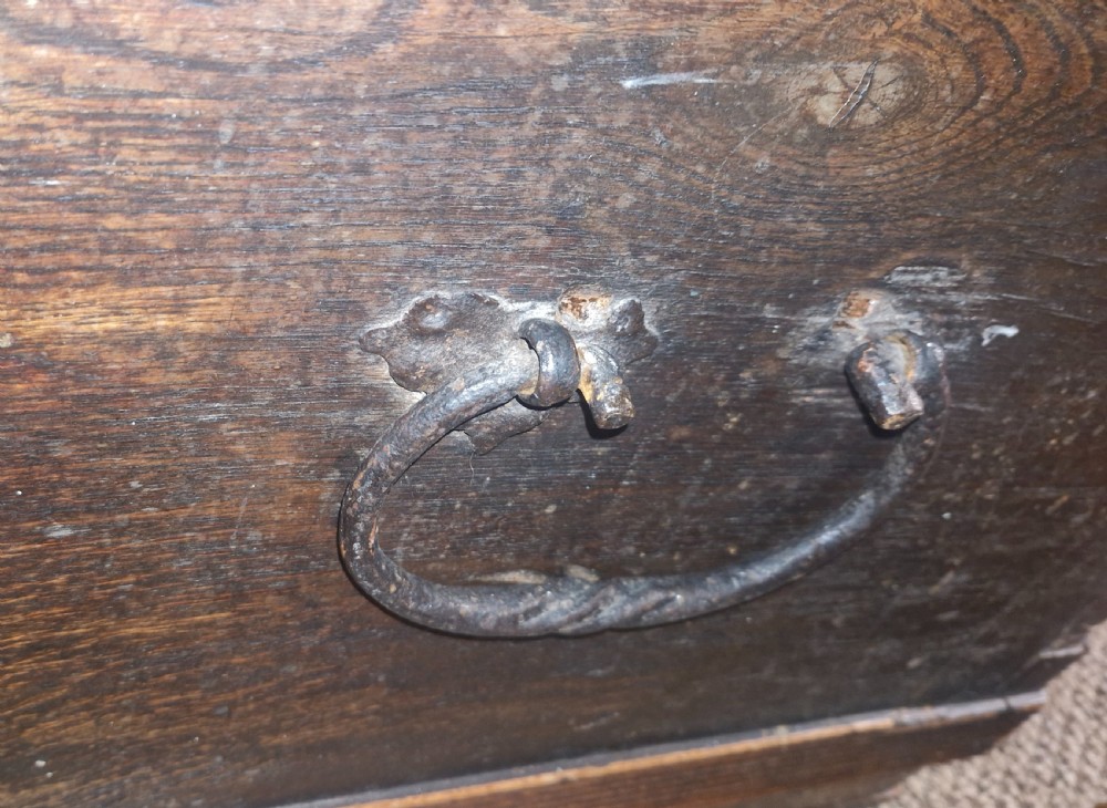 A dark brown 18th-century carved oak blanket chest featuring rosette relief carvings, a carved top frieze, and a central iron escutcheon. View XIII