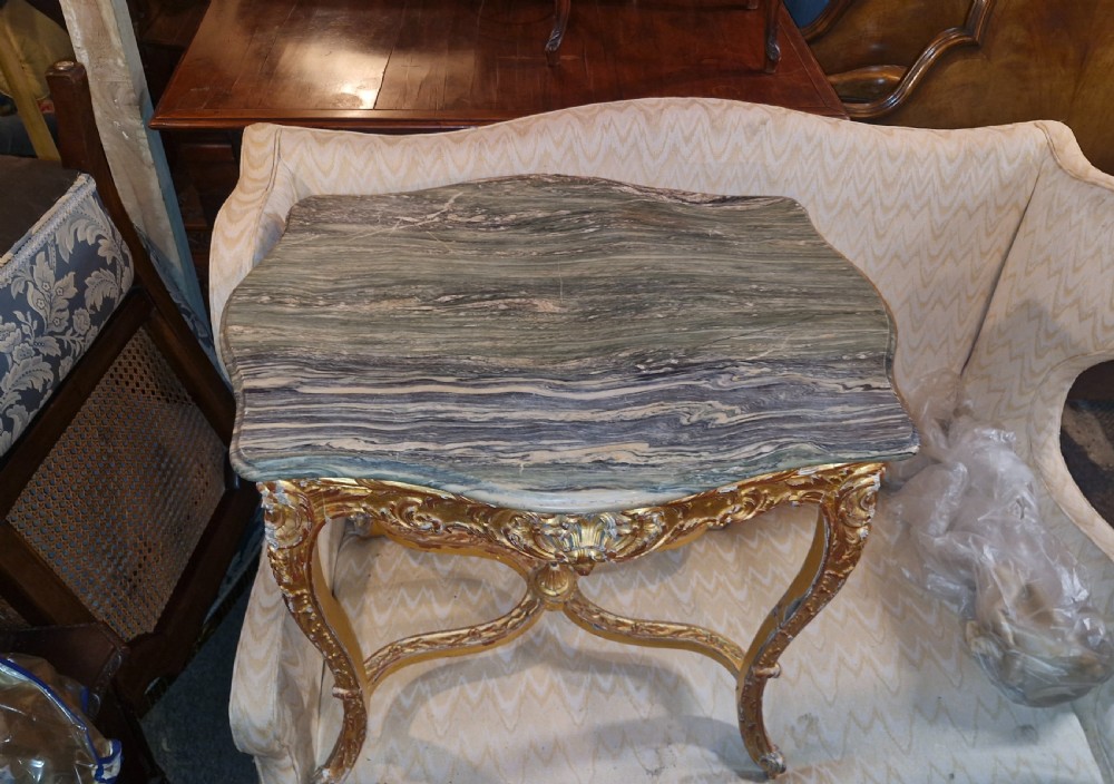 A carved giltwood occasional table featuring cabriole legs, ornate scroll carving, and a shaped veined green marble top. View II