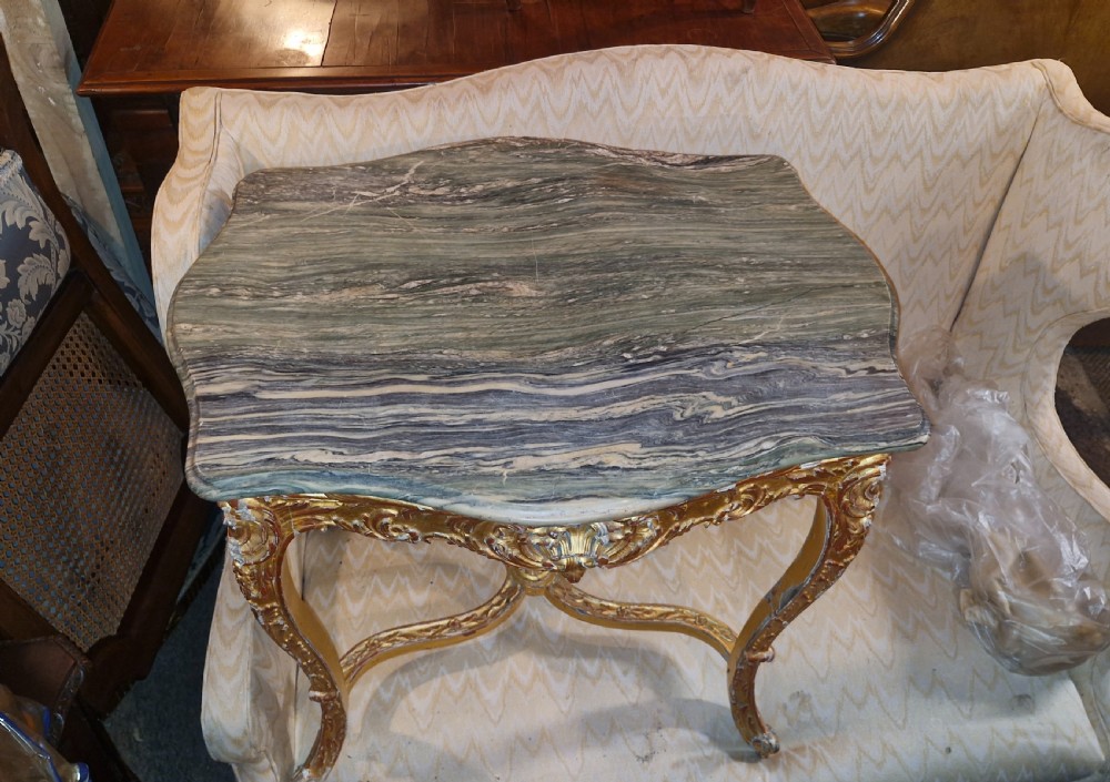 A carved giltwood occasional table featuring cabriole legs, ornate scroll carving, and a shaped veined green marble top. View III