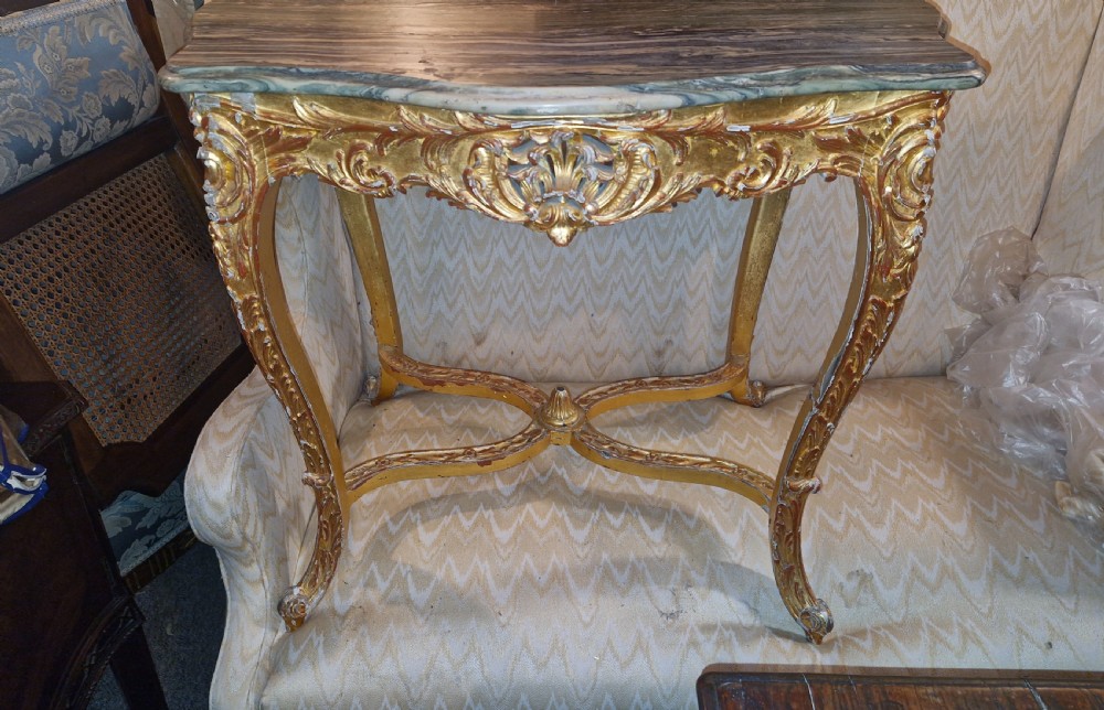 A carved giltwood occasional table featuring cabriole legs, ornate scroll carving, and a shaped veined green marble top. View VIII