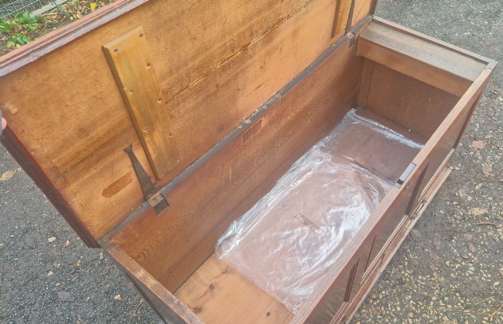 A late Georgian oak blanket chest featuring three fielded front panels, two lower drawers with brass drop handles, and a hinged lid. View VIII