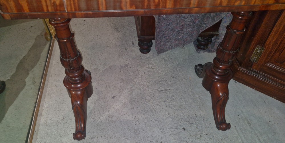 A Regency mahogany writing table featuring a central leather-inset writing surface and two hinged side flaps revealing interior storage compartments. View III