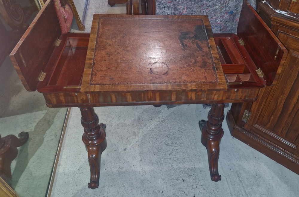 A Regency mahogany writing table featuring a central leather-inset writing surface and two hinged side flaps revealing interior storage compartments. View VI