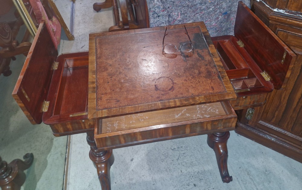 A Regency mahogany writing table featuring a central leather-inset writing surface and two hinged side flaps revealing interior storage compartments. View XI
