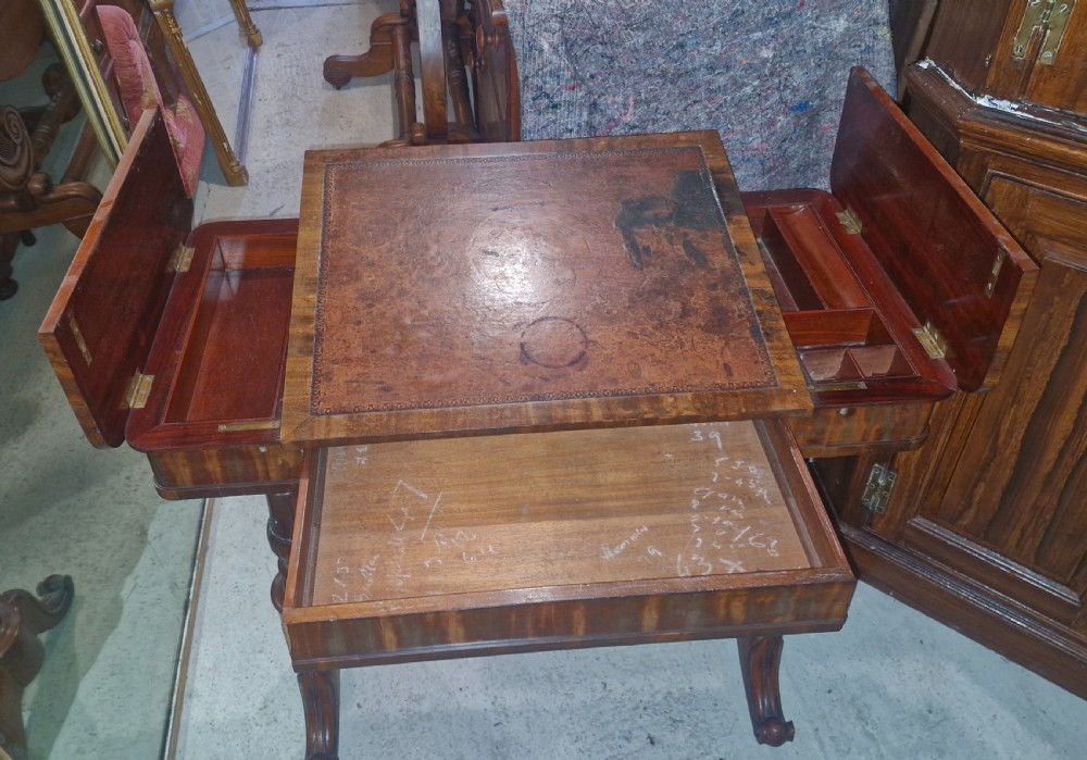 A Regency mahogany writing table featuring a central leather-inset writing surface and two hinged side flaps revealing interior storage compartments. View XVII