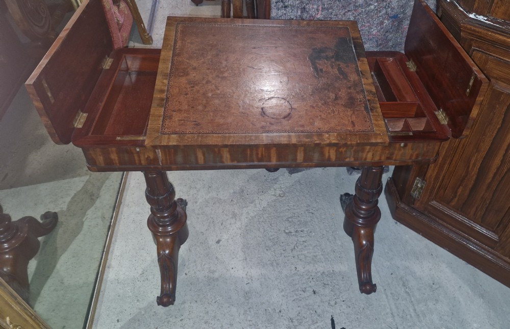 A Regency mahogany writing table featuring a central leather-inset writing surface and two hinged side flaps revealing interior storage compartments.