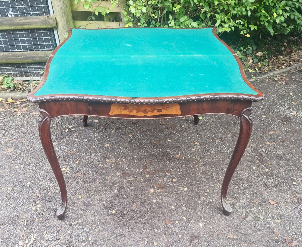 An 18th-century mahogany games table featuring a serpentine front, cabriole legs with carved knees, and marquetry inlay on the top. View IX