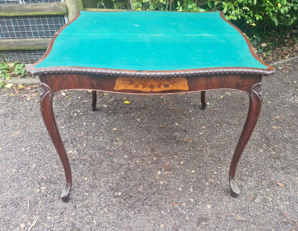 An 18th-century mahogany games table featuring a serpentine front, cabriole legs with carved knees, and marquetry inlay on the top. View X