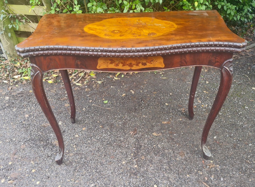 An 18th-century mahogany games table featuring a serpentine front, cabriole legs with carved knees, and marquetry inlay on the top. View XIX