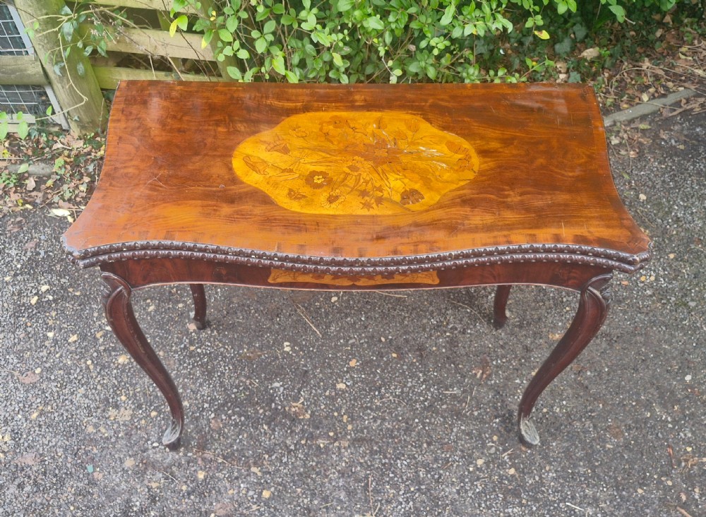 An 18th-century mahogany games table featuring a serpentine front, cabriole legs with carved knees, and marquetry inlay on the top. View XXI