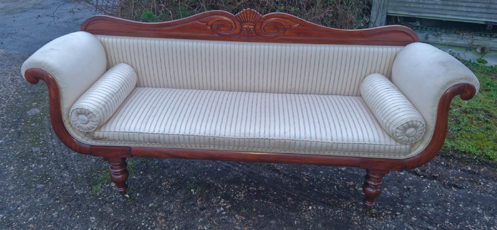A Regency mahogany scroll-end sofa upholstered in cream striped fabric with matching bolster cushions and turned legs.