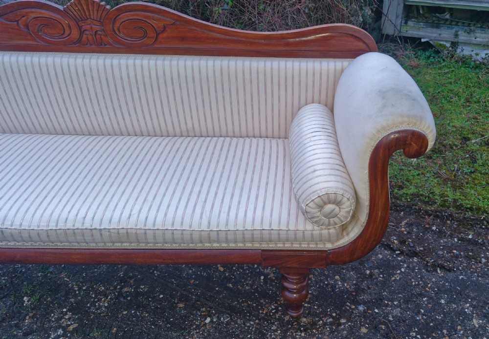 A Regency mahogany scroll-end sofa upholstered in cream striped fabric with matching bolster cushions and turned legs. View IX