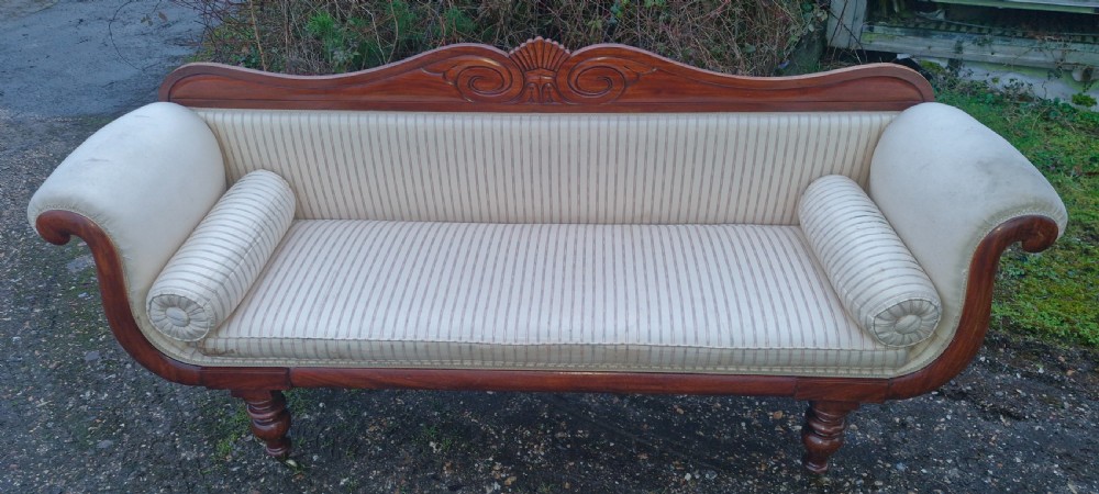 A Regency mahogany scroll-end sofa upholstered in cream striped fabric with matching bolster cushions and turned legs. View X