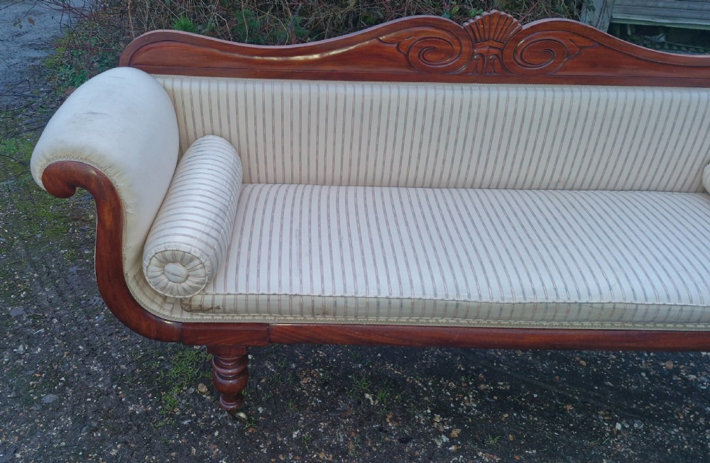 A Regency mahogany scroll-end sofa upholstered in cream striped fabric with matching bolster cushions and turned legs. View XI
