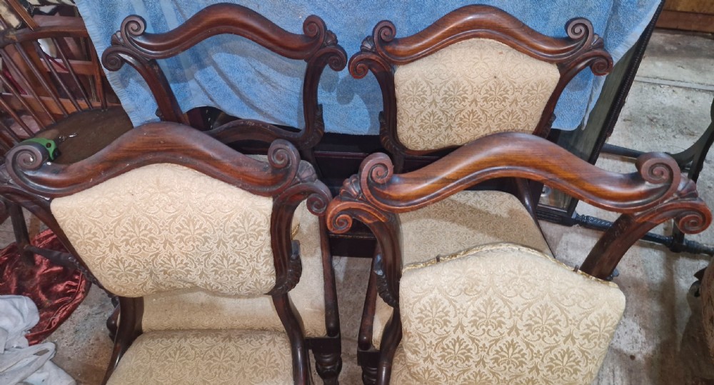 A set of early Victorian rosewood dining chairs with carved scroll crest rails, beige damask upholstered seat and back pads, and turned front legs. View IV