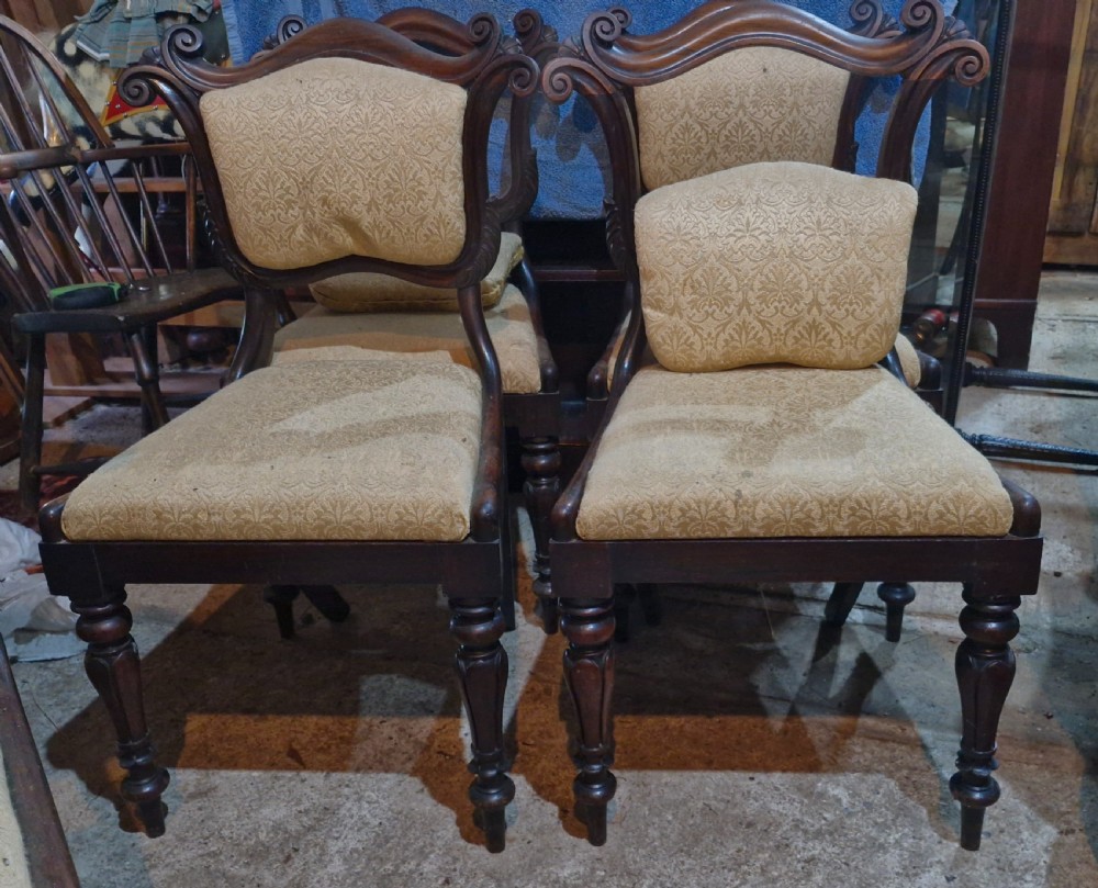 A set of early Victorian rosewood dining chairs with carved scroll crest rails, beige damask upholstered seat and back pads, and turned front legs. View X