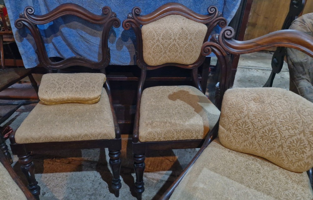 A set of early Victorian rosewood dining chairs with carved scroll crest rails, beige damask upholstered seat and back pads, and turned front legs. View XII