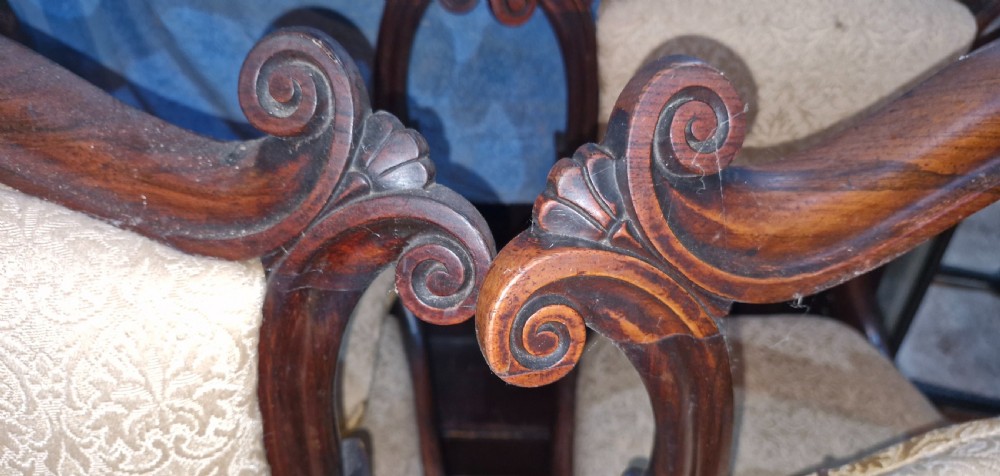 A set of early Victorian rosewood dining chairs with carved scroll crest rails, beige damask upholstered seat and back pads, and turned front legs. View XIV