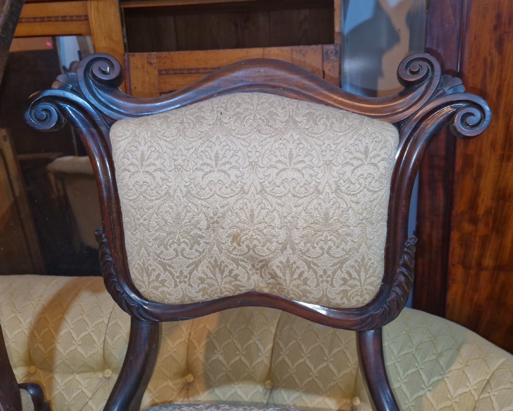 A set of early Victorian rosewood dining chairs with carved scroll crest rails, beige damask upholstered seat and back pads, and turned front legs. View XVI
