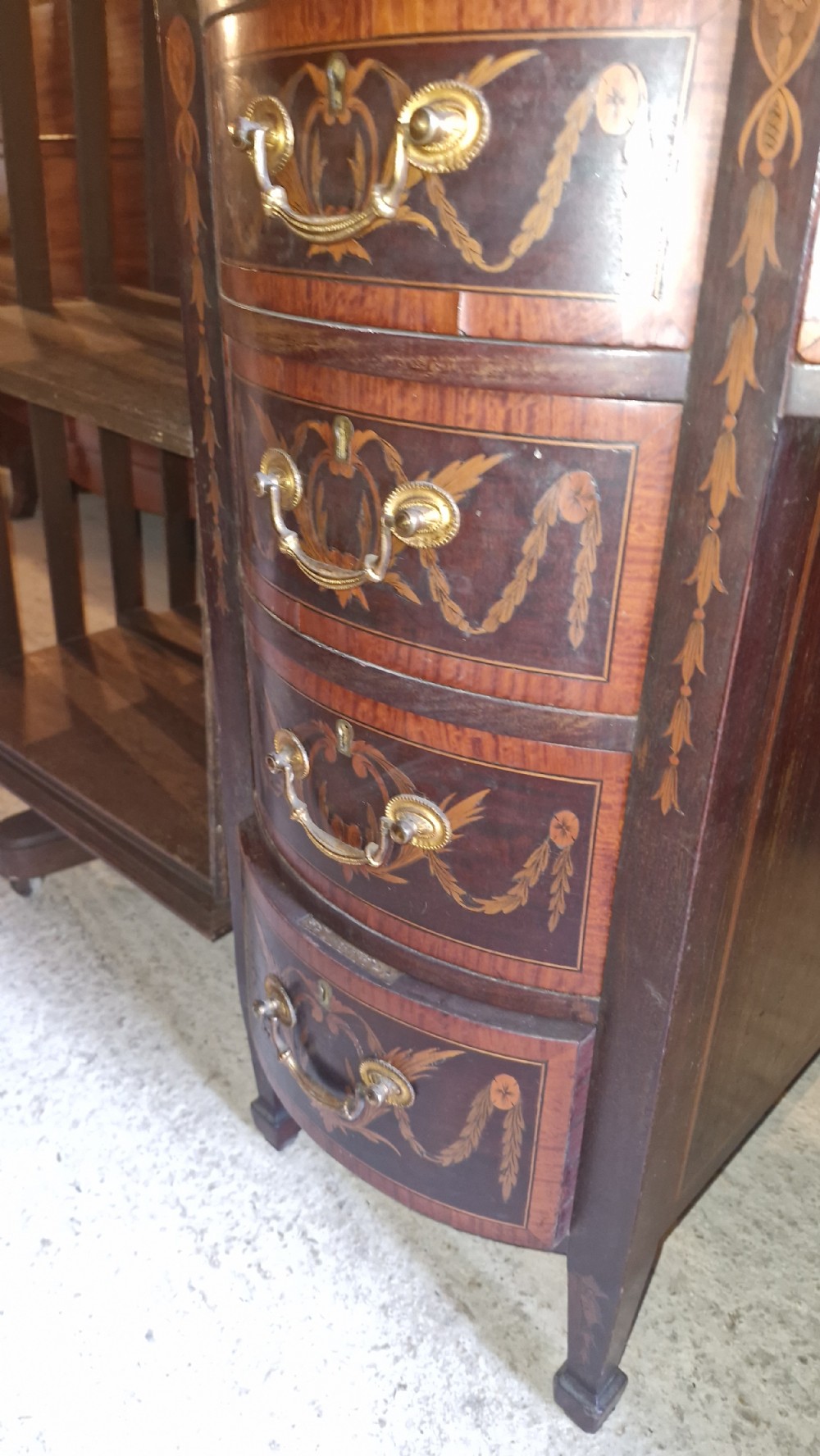 A late Victorian inlaid mahogany kneehole writing desk featuring a green leather insert, multiple drawers with brass handles, and detailed floral marquetry. View VI