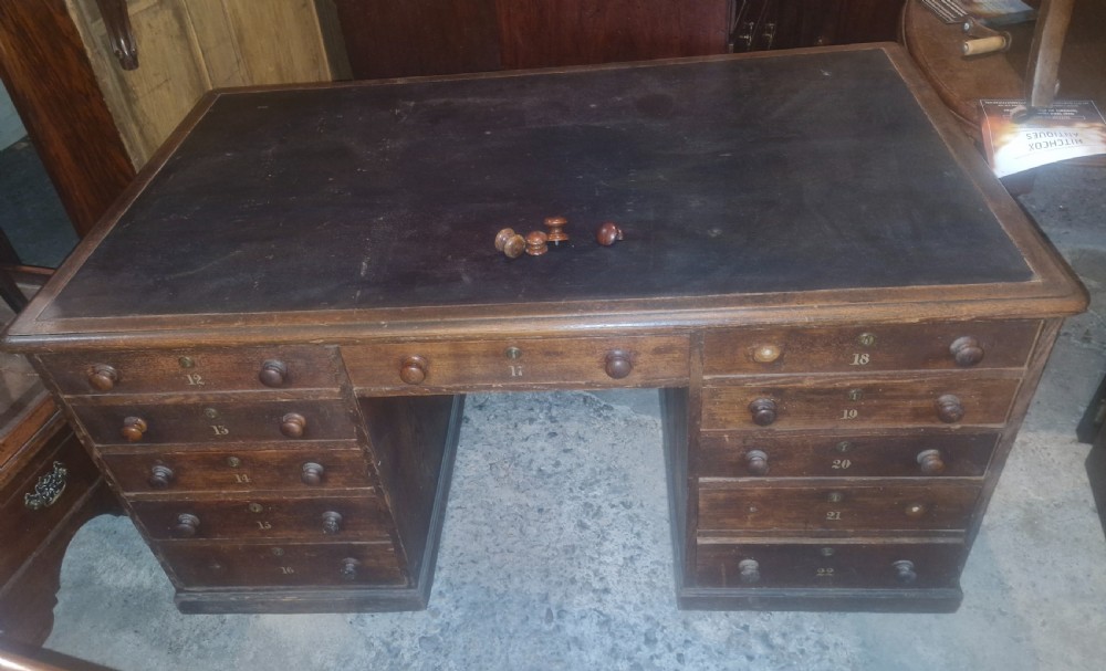 A nineteenth-century dark wood pedestal desk featuring a leather writing surface, turned wooden knobs, and numbered drawer fronts. View II