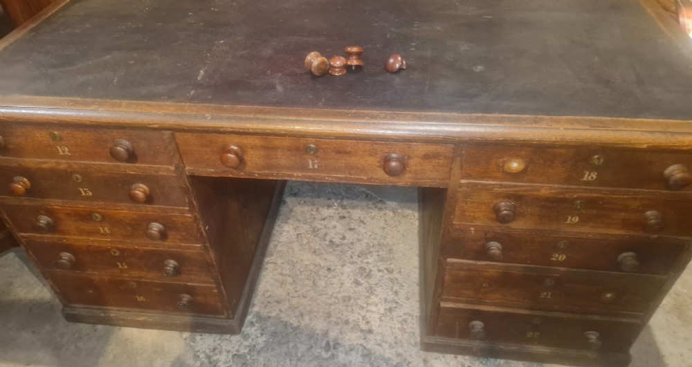 A nineteenth-century dark wood pedestal desk featuring a leather writing surface, turned wooden knobs, and numbered drawer fronts. View III