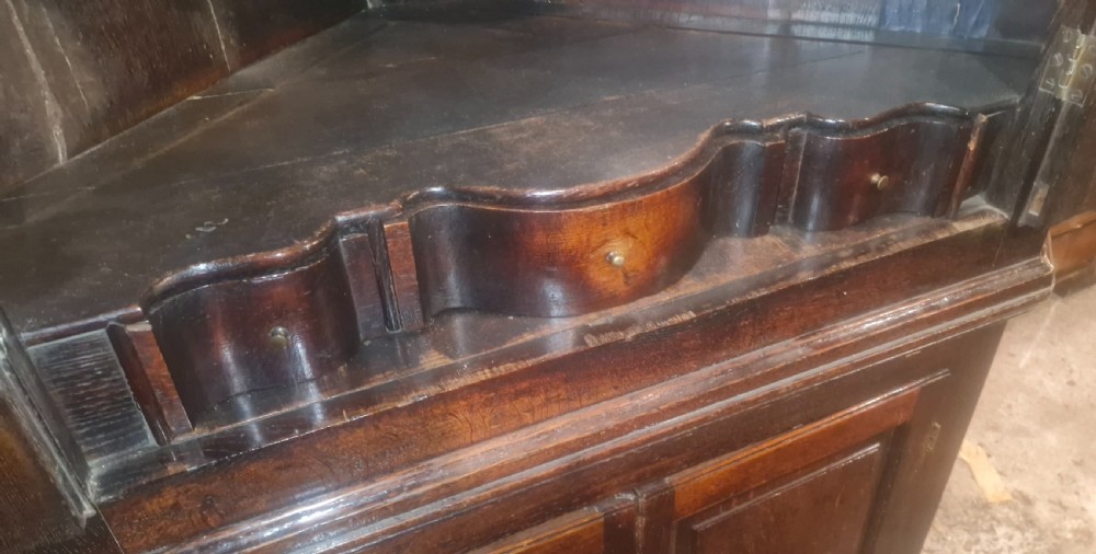 A tall dark oak Georgian two-part corner cupboard featuring fielded panel doors, fluted side pilasters, and a decorative cornice. View VIII