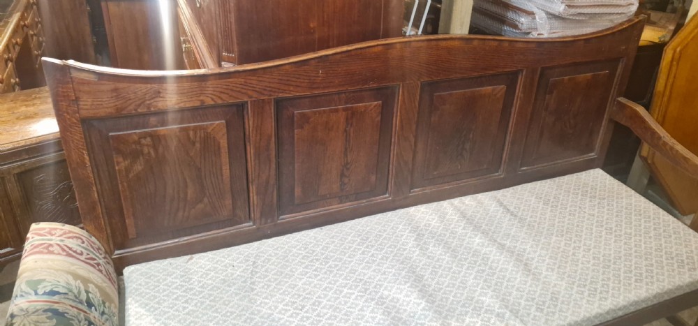 An antique dark oak settle featuring a four-panel backboard, upholstered seat cushion, patterned armrests, and square legs. View XI