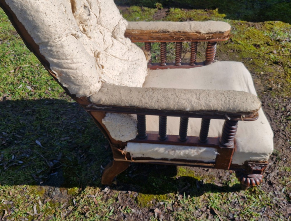 A mid-19th century Victorian mahogany armchair with turned spiral arm supports, brass castors, and exposed original upholstery lining. View III