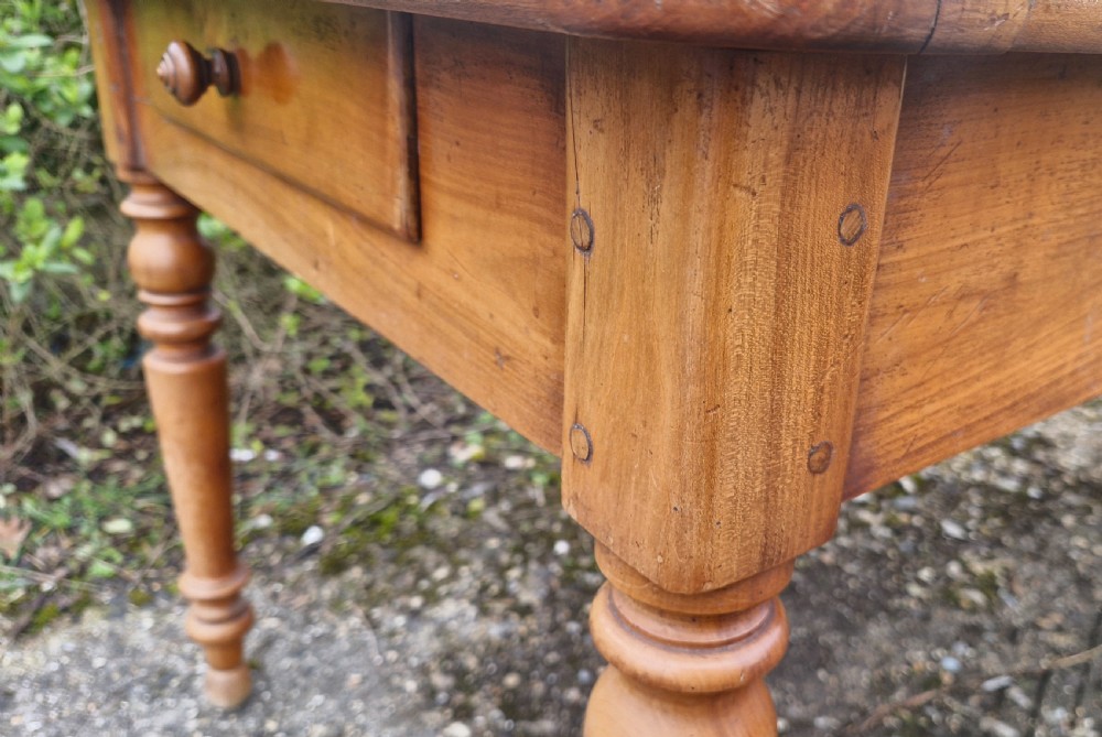 A long rectangular wooden French farmhouse dining table featuring turned legs, an open side drawer, and an extended pull-out bread slide. View X
