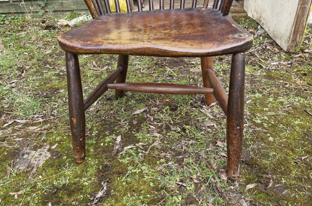 An early nineteenth-century West Country Windsor armchair featuring a high curved hoop back with slender spindles, shaped armrests, and a solid shaped wooden seat. View II