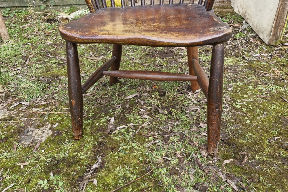 An early nineteenth-century West Country Windsor armchair featuring a high curved hoop back with slender spindles, shaped armrests, and a solid shaped wooden seat. View XIII