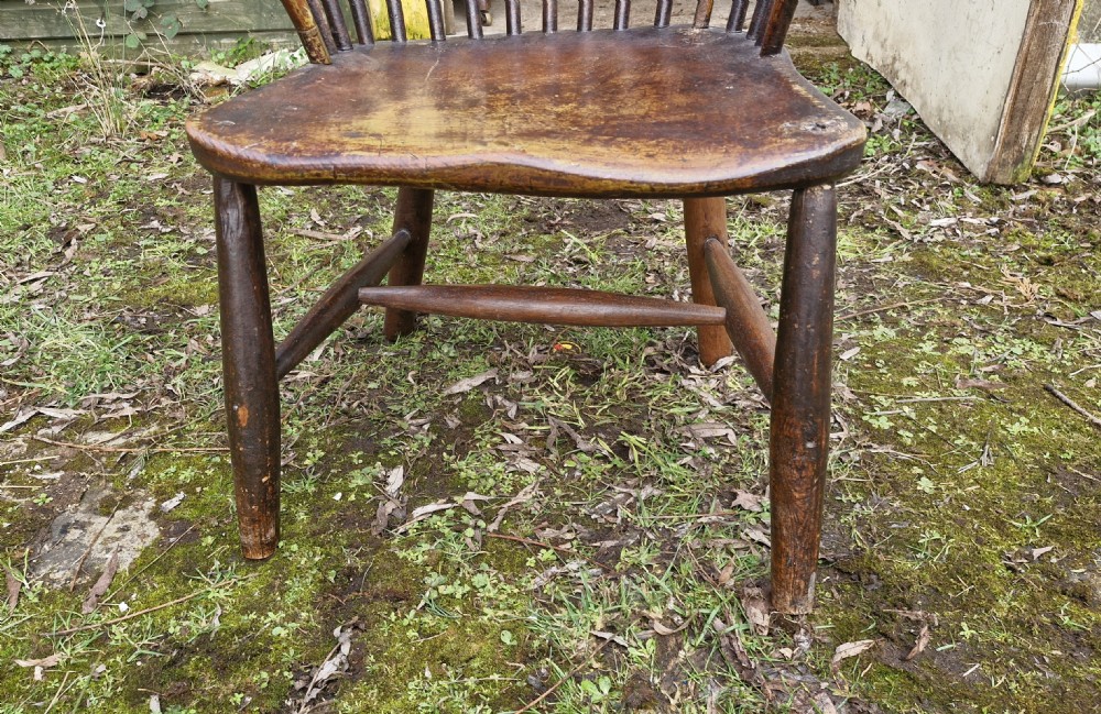 An early nineteenth-century West Country Windsor armchair featuring a high curved hoop back with slender spindles, shaped armrests, and a solid shaped wooden seat. View XIV