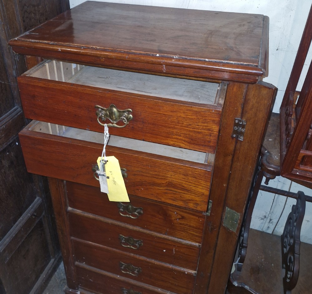 A tall, narrow Victorian walnut Wellington chest featuring seven graduated drawers with decorative brass handles and a side locking bar. View III