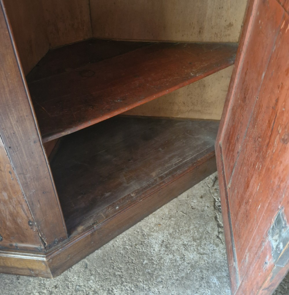 An early 18th-century floor-standing wooden corner cupboard featuring an upper door with an arched raised panel, a lower panelled door, and brass H-hinges. View VII