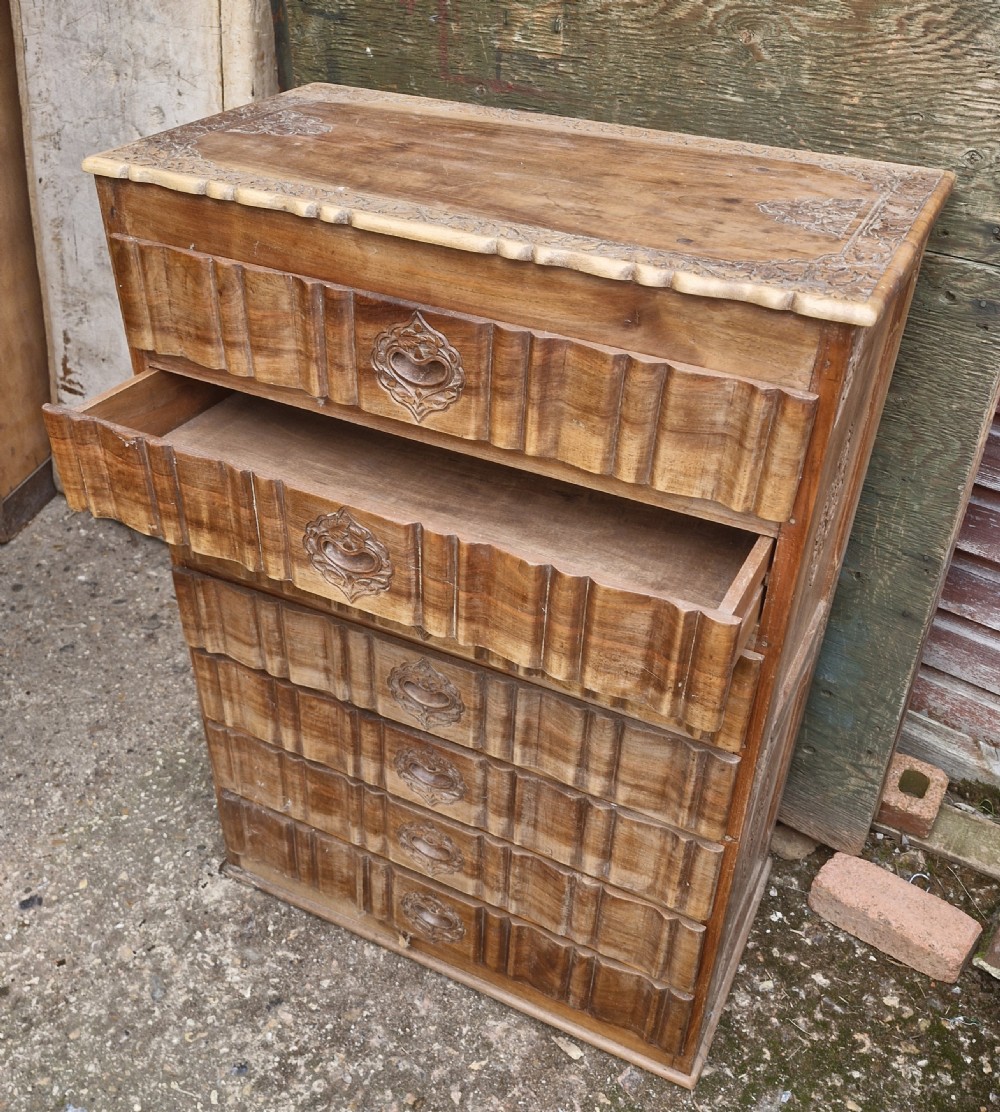 A 1930s Anglo-Indian carved wooden tallboy chest featuring seven stacked drawers with carved central escutcheon handles and fluted drawer fronts. View III