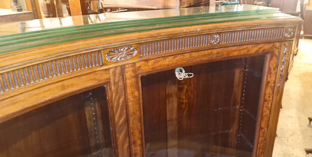 An Edwardian mahogany concave bookcase featuring twin glazed doors, fluted frieze moulding, and carved floral detailing. View VII