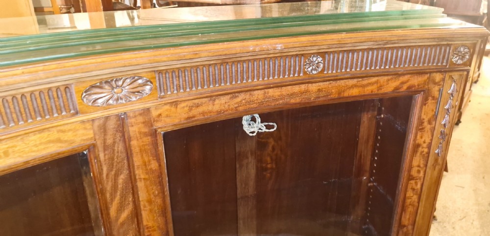 An Edwardian mahogany concave bookcase featuring twin glazed doors, fluted frieze moulding, and carved floral detailing. View VIII
