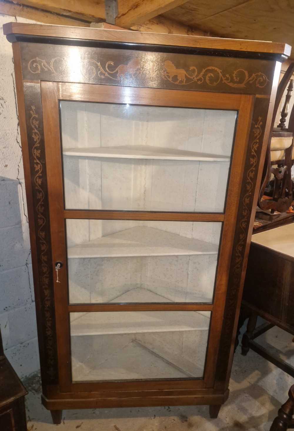 A tall Danish wooden corner cabinet featuring a glazed front door, decorative inlaid scrolling borders, and internal shelves painted off-white. View II