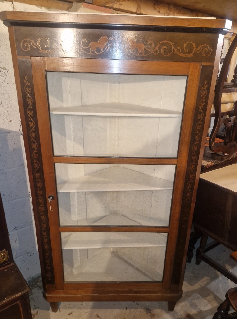 A tall Danish wooden corner cabinet featuring a glazed front door, decorative inlaid scrolling borders, and internal shelves painted off-white. View VIII